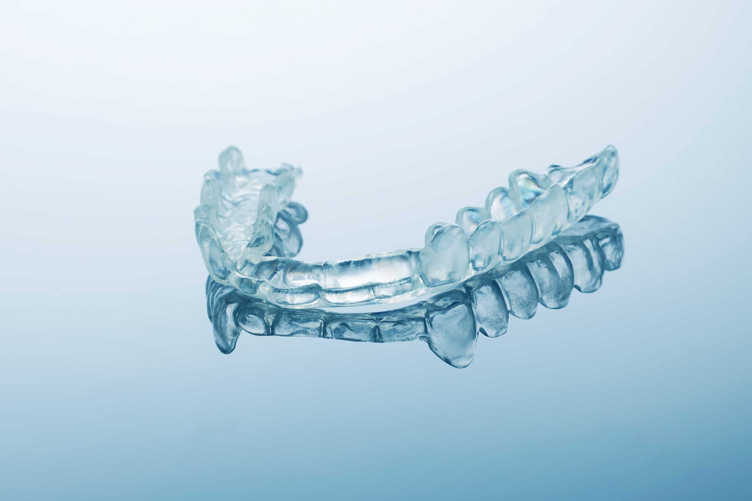 A clear dental guard photographed on a soft blue background